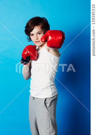 Portrait, boy and kid with boxing gloves, fitness and confident fist on a blue studio background. Child development, punch and fighting with workout, combat and training with fun and mockup space 139595310