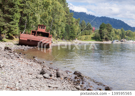 Teletskoye lake, coastal landscape with ship wreck. An abandoned rusty barge Teletskoye lake, coastal landscape with ship wreck. An abandoned rusty barge 139595565