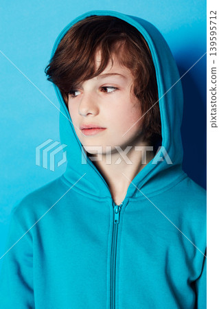 Studio, fashion or young kid in hoodie, trendy apparel or stylish outfit isolated on blue background. Cotton fabric, adolescent boy and youth child with clothes, casual outfit and looking at style 139595712