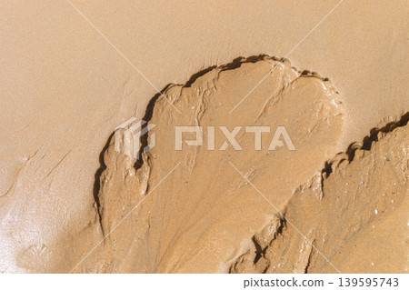 Sand pattern resembling a leaf shape on a beach shore Close up Top view Sand pattern resembling a leaf shape on a beach shore Close up Top view 139595743