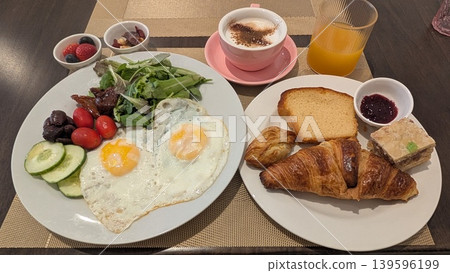 Large breakfast plates with bread, fried eggs, salad, nuts, fruits, and drinks Large breakfast plates with bread, fried eggs, salad, nuts, fruits, and drinks 139596199