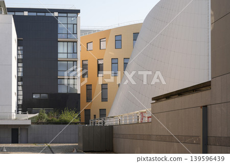 Modern curved urban architecture beside residential apartments under spring sunlight Modern curved urban architecture beside residential apartments under spring sunlight 139596439