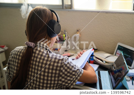 Teenage girl in headphones at the table Teenage girl in headphones at the table 139596742