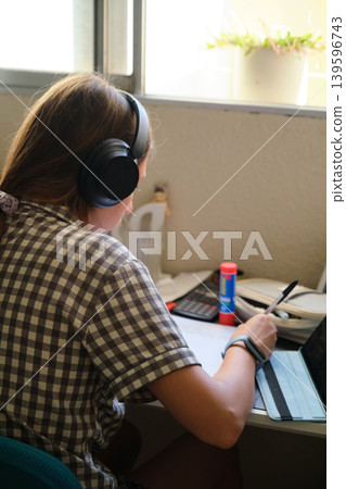 Teenage girl in headphones at the table Teenage girl in headphones at the table 139596743