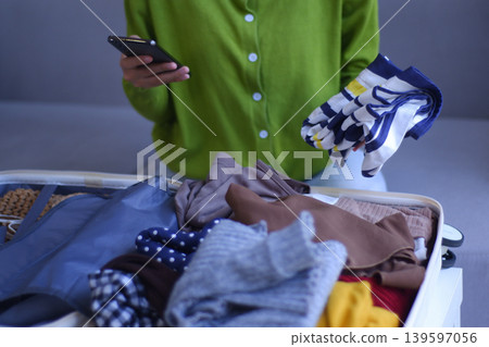 Young women folding clothes, packing luggage for holiday trip. 139597056