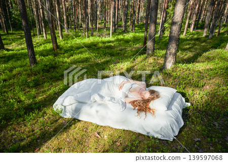 Woman sleeps on a mattress in the summer forest Woman sleeps on a mattress in the summer forest 139597068