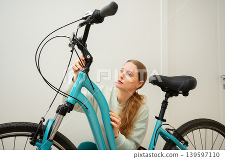 A woman examines a bicycle A woman examines a bicycle 139597110
