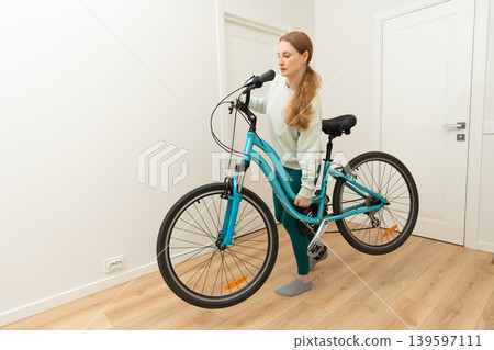 A woman carries a bicycle in an apartment A woman carries a bicycle in an apartment 139597111