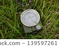 Olive compass lies in green grass. Travel, adventure, and navigation concepts. 139597261