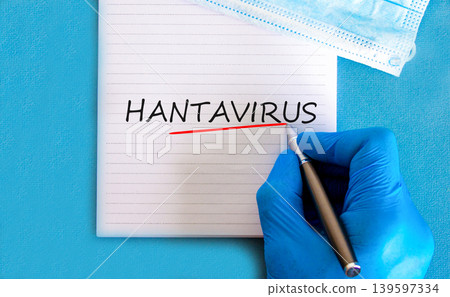 Hantavirus medical words symbol. Concept words Hantavirus on beautiful white note. Beautiful blue background. Doctor hand with pen. Blue glove. Medical mask. Medical Hantavirus concept. Copy space. Hantavirus medical words symbol. Concept words Hantavirus on beautiful white note. Beautiful blue background. Doctor hand with pen. Blue glove. Medical mask. Medical Hantavirus concept. Copy space. 139597334