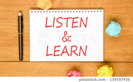 Listen and learn words symbol. Concept words Listen and learn on beautiful white note. Beautiful wooden background. Black pen. Colored paper. Business listen and learn support concept. Copy space. 139597456