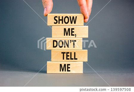 Tell or show symbol. Concept words Show me, do not tell me on beautiful wooden blocks. Beautiful grey paper background. Businessman hand. Business tell or show concept. Copy space. 139597508