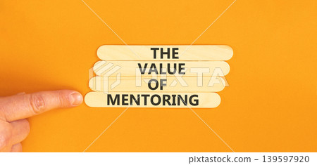 The value of mentoring words symbol. Concept words The value of mentoring on beautiful wooden sticks. Beautiful orange background. Businessman hand. Business the value of mentoring concept. Copy space The value of mentoring words symbol. Concept words The value of mentoring on beautiful wooden sticks. Beautiful orange background. Businessman hand. Business the value of mentoring concept. Copy space 139597920