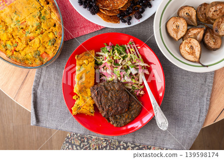 A healthy breakfast or lunch is served at a home table. The meal includes potato pie with beef patties, fresh salad, baked pears, and pancakes for dessert A healthy breakfast or lunch is served at a home table. The meal includes potato pie with beef patties, fresh salad, baked pears, and pancakes for dessert 139598174