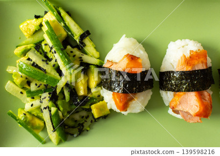 A plate shows a salad made with nori, fresh cucumbers, and avocado next to nigiri sushi topped with red fish. This dish is suitable for breakfast or lunch A plate shows a salad made with nori, fresh cucumbers, and avocado next to nigiri sushi topped with red fish. This dish is suitable for breakfast or lunch 139598216
