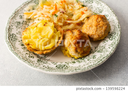Food is arranged on a plate. Baked potato baskets are filled with mashed potatoes. There are turkey meatballs and a serving of fermented cabbage on the side Food is arranged on a plate. Baked potato baskets are filled with mashed potatoes. There are turkey meatballs and a serving of fermented cabbage on the side 139598224