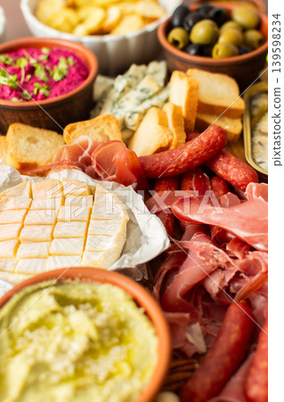 Taste a variety of flavors with this charcuterie board filled with cheese, sausages, hummus, nuts, and fresh sandwiches, perfect for any gathering Taste a variety of flavors with this charcuterie board filled with cheese, sausages, hummus, nuts, and fresh sandwiches, perfect for any gathering 139598234