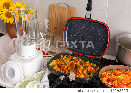 Preparing squash caviar in the kitchen using a blender, a pot, and a bowl. Tools are set up on a counter surrounded by fresh ingredients and sunflowers 139598255