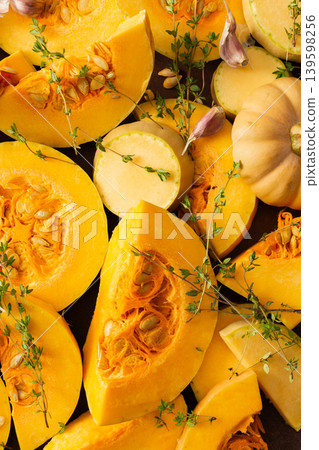 Slices of yellow squash are laid out on a wooden surface. Fresh thyme sprigs are placed on the squash. This scene shows preparation for cooking a meal or dish Slices of yellow squash are laid out on a wooden surface. Fresh thyme sprigs are placed on the squash. This scene shows preparation for cooking a meal or dish 139598256