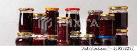Jars filled with homemade strawberry and raspberry jam are neatly arranged on a table, ready for winter storage and use in meals and treats during the chilly season, banner Jars filled with homemade strawberry and raspberry jam are neatly arranged on a table, ready for winter storage and use in meals and treats during the chilly season, banner 139598282