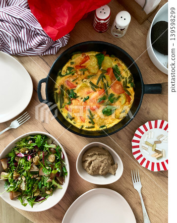 Baked vegetables with eggs sit on a plate next to a salad made from arugula and Brussels sprouts. A bowl of liver pate completes the meal with healthy choices Baked vegetables with eggs sit on a plate next to a salad made from arugula and Brussels sprouts. A bowl of liver pate completes the meal with healthy choices 139598299