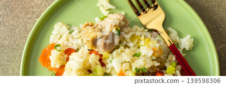 Boiled rice is served on a green plate alongside chicken breast, Brussels sprouts, and zucchini slices. A glass of water sits nearby, completing the meal, banner Boiled rice is served on a green plate alongside chicken breast, Brussels sprouts, and zucchini slices. A glass of water sits nearby, completing the meal, banner 139598306
