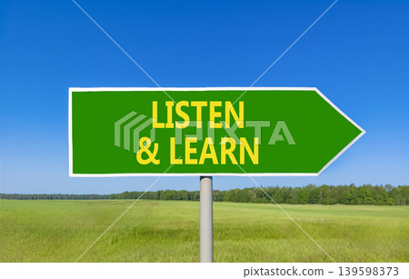 Listen and learn words symbol. Concept words Listen and learn on beautiful green road sign. Beautiful blue sky green field background. Business listen and learn support concept. Copy space. 139598373