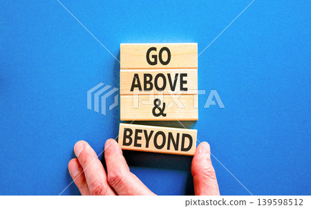 Go above and beyond symbol. Concept words Go above and beyond on beautiful wooden blocks. Beautiful blue background. Businessman hand. Business motivational Go above and beyond concept. Copy space. Go above and beyond symbol. Concept words Go above and beyond on beautiful wooden blocks. Beautiful blue background. Businessman hand. Business motivational Go above and beyond concept. Copy space. 139598512