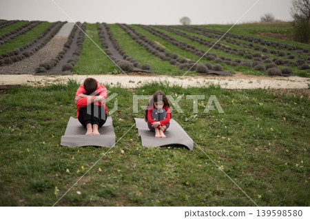 Practicing mindfulness in a tranquil lavender field during a cloudy afternoon with two individuals engaging in yoga and meditation ceremony 139598580