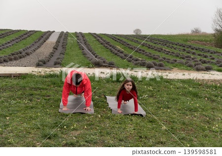 Two children practice yoga among lavender fields in spring, embracing nature and wellness in a serene outdoor setting while cultivating mindfulness and strength 139598581