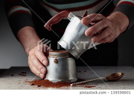Man is prepared coffee in a classic Italian aluminium moka pot. Man is prepared coffee in a classic Italian aluminium moka pot. 139598601