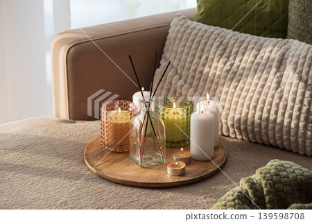 Candles and Reed Diffuser on Wooden Tray. Cozy Home Decor lifestyle with Cushions Candles and Reed Diffuser on Wooden Tray. Cozy Home Decor lifestyle with Cushions 139598708