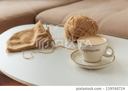 Knitting Project with Cup of Cappuccino on White Table in Cozy Setting Knitting Project with Cup of Cappuccino on White Table in Cozy Setting 139598724