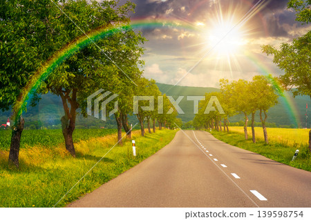 sunset over deciduous trees along the country road in to mountains. beautiful summer landscape of a slovakia countryside. beautiful travel background. journey through europe. weather with rainbow sunset over deciduous trees along the country road in to mountains. beautiful summer landscape of a slovakia countryside. beautiful travel background. journey through europe. weather with rainbow 139598754