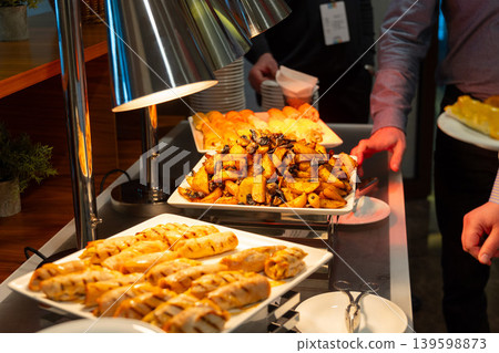 Person serving roasted potatoes from a buffet station 139598873