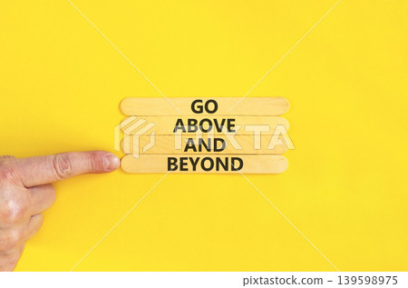 Go above and beyond symbol. Concept words Go above and beyond on beautiful wooden sticks. Beautiful yellow background. Businessman hand. Business motivational Go above and beyond concept. Copy space. Go above and beyond symbol. Concept words Go above and beyond on beautiful wooden sticks. Beautiful yellow background. Businessman hand. Business motivational Go above and beyond concept. Copy space. 139598975