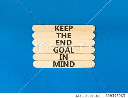Keep the end goal in mind symbol. Concept words Keep the end goal in mind on beautiful wooden sticks. Beautiful blue paper background. Business keep the end goal in mind concept. Copy space. 139598985