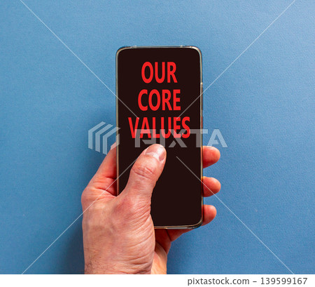 Our core values words symbol. Concept words Our core values on beautiful phone screen. Beautiful blue background. Businessman hand. Business our core values motivational support concept. Copy space. 139599167