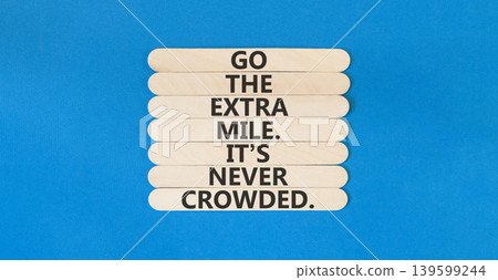 Go the extra mile symbol. Concept words Go the extra mile. It's never crowded on beautiful wooden sticks. Beautiful blue paper background. Business go the extra mile concept. Copy space. 139599244