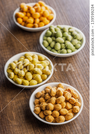 Assorted Coated Peanuts in White Bowls on Wooden Table - Crunchy Flavored Snack Mix Assorted Coated Peanuts in White Bowls on Wooden Table - Crunchy Flavored Snack Mix 139599284