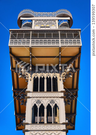Close view of Santa Justa lift elevator, Lisbon, Portugal connecting Baixa district with Largo do Carmo on sunny day. Iron tower, blue sky with clouds, iconic city landmark, travel destination Close view of Santa Justa lift elevator, Lisbon, Portugal connecting Baixa district with Largo do Carmo on sunny day. Iron tower, blue sky with clouds, iconic city landmark, travel destination 139599307