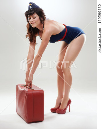 Travel, flight attendant and a woman with a heavy suitcase in studio isolated on white background. Luggage, air hostess and person with bag, retro steward and fashion of vintage model on journey Travel, flight attendant and a woman with a heavy suitcase in studio isolated on white background. Luggage, air hostess and person with bag, retro steward and fashion of vintage model on journey 139599380