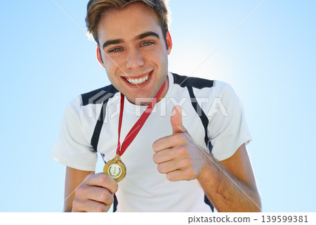Athlete, portrait and thumbs up with medal for sports achievement, success and yes in competition. Face of winner, runner or man with like, prize or good job hands, emoji and gold award on a blue sky Athlete, portrait and thumbs up with medal for sports achievement, success and yes in competition. Face of winner, runner or man with like, prize or good job hands, emoji and gold award on a blue sky 139599381