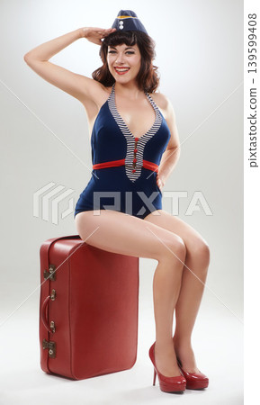 Fashion, travel and portrait of a flight attendant on suitcase in studio isolated on a white background. Luggage, air hostess and smile of woman, retro steward and person salute on bag for journey Fashion, travel and portrait of a flight attendant on suitcase in studio isolated on a white background. Luggage, air hostess and smile of woman, retro steward and person salute on bag for journey 139599408