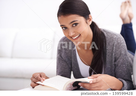 Portrait of woman, reading book on sofa and learning for home education, literature or language. Young Mexican student relax in living room and lounge with novel or story for knowledge or studying 139599428