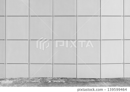 Minimal architectural facade showing a grid of square metal panels with visible joints 139599464