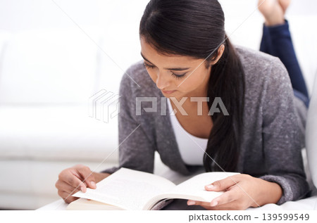Young woman, reading book on sofa and learning for home education, literature or language with leisure. Student or person relax in living room or lounge with novel or story for knowledge or studying Young woman, reading book on sofa and learning for home education, literature or language with leisure. Student or person relax in living room or lounge with novel or story for knowledge or studying 139599549