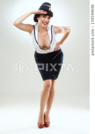 Portrait, smile and pin up girl or flight attendant in studio on gray background for vintage fashion. Travel, greeting or salute with happy young air hostess in work uniform for welcome and service 139599686