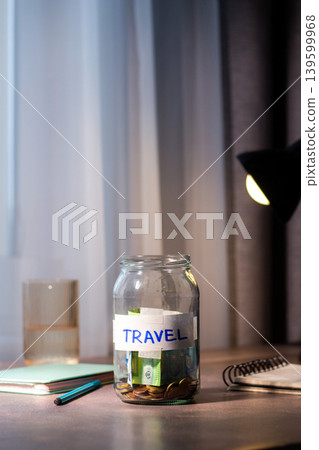 Savings jar for TRAVEL on table. Close up of money in transparent container representing financial planning and goal achievement Savings jar for TRAVEL on table. Close up of money in transparent container representing financial planning and goal achievement 139599968