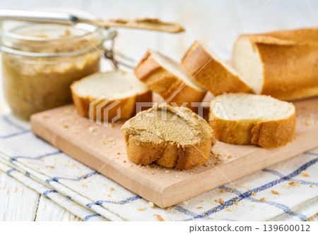 Creamy pate curls on a slice of baguette bread on a white table, selective focus. Creamy pate curls on a slice of baguette bread on a white table, selective focus. 139600012